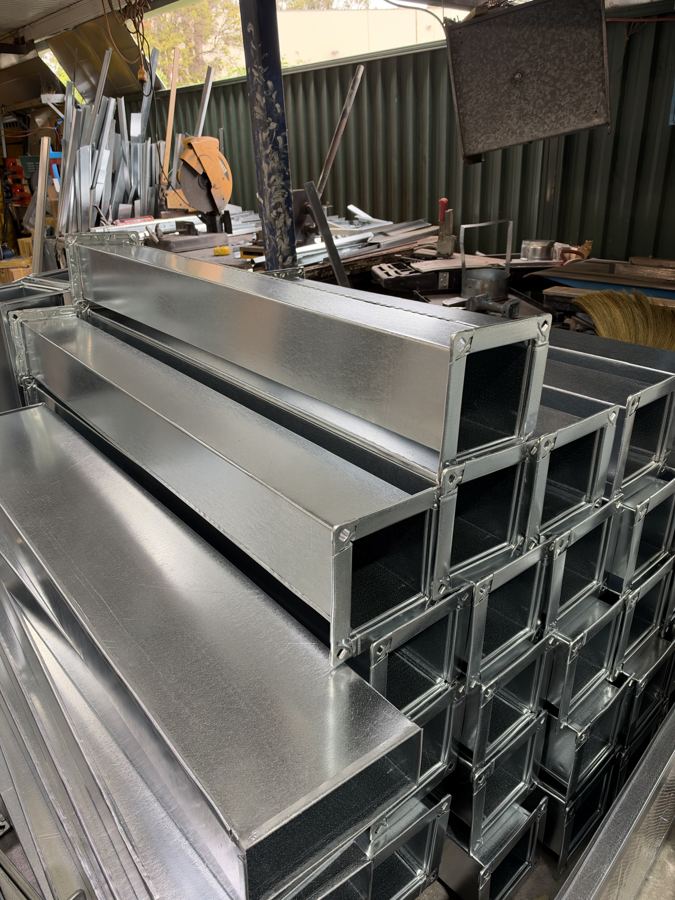 Lengths of rectangular duct stacked in the workshop